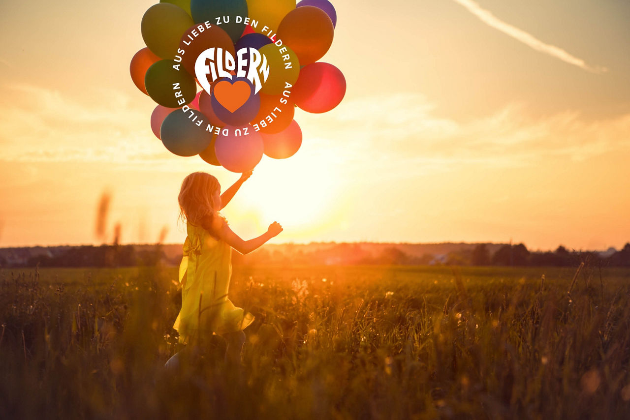Kind mit Luftballons auf einem Feld