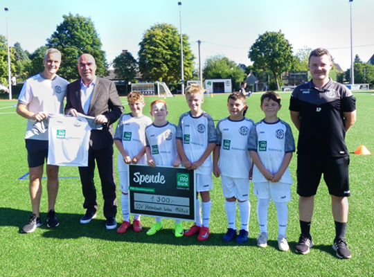 Eine junge Fußballmannschaft nimmt einen Spendenscheck entgegen