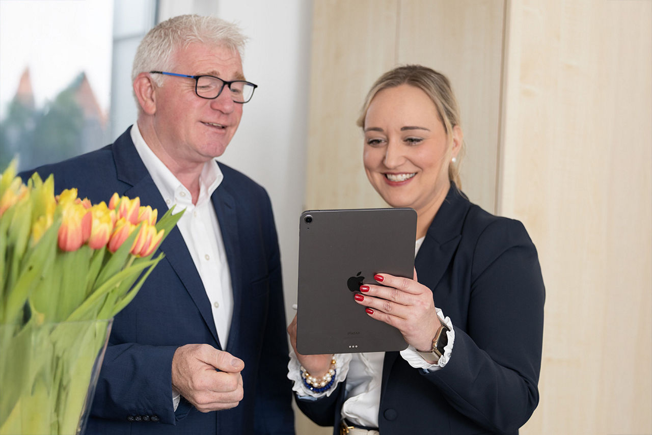 Helmut Schulte und Annika Schepers schauen auf ein Tablet.