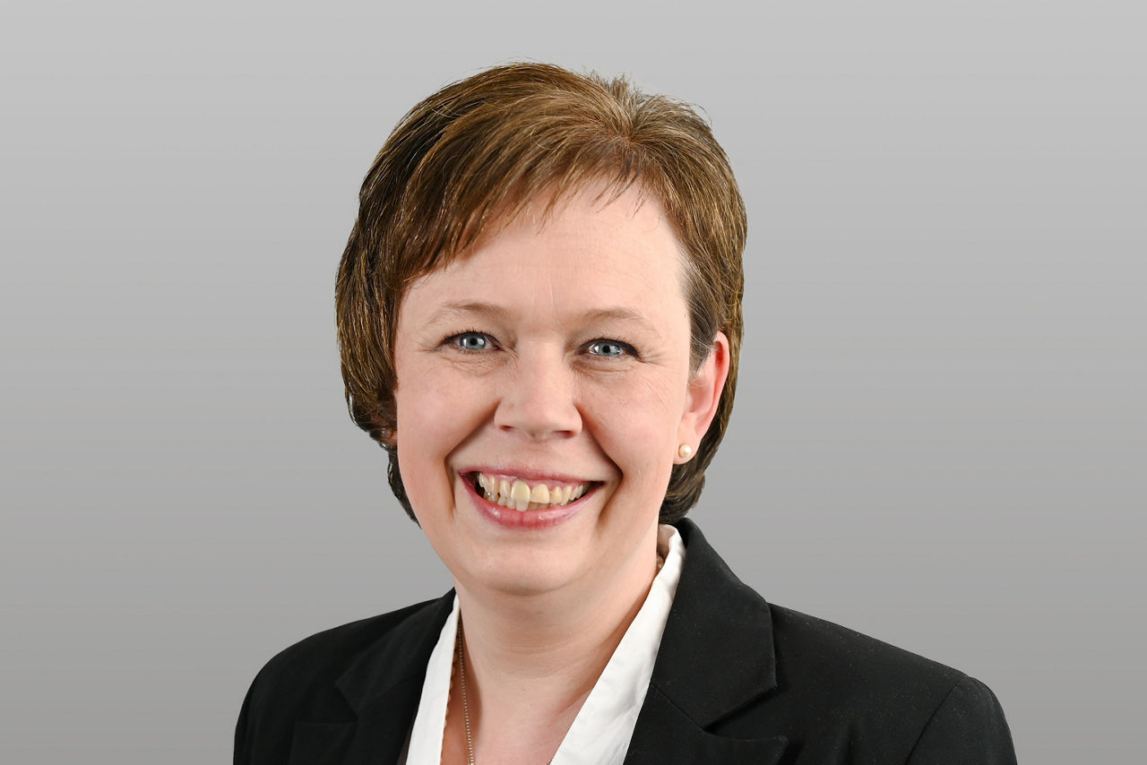 Servicemitarbeiterin Maud Helsberg-Kaul vor grauen Hintergrund