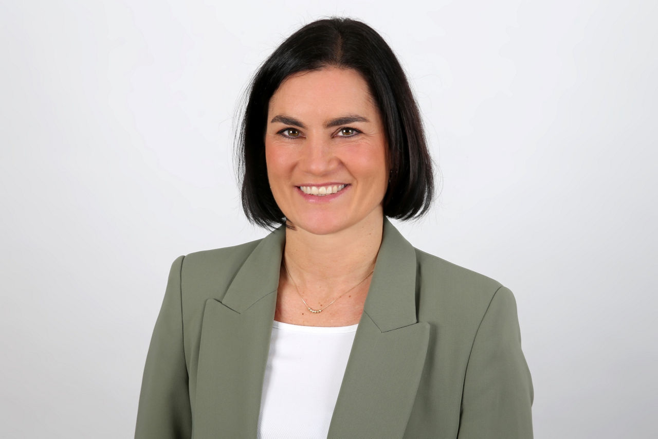 Eine lächelnder Frau schaut in die Kamera.