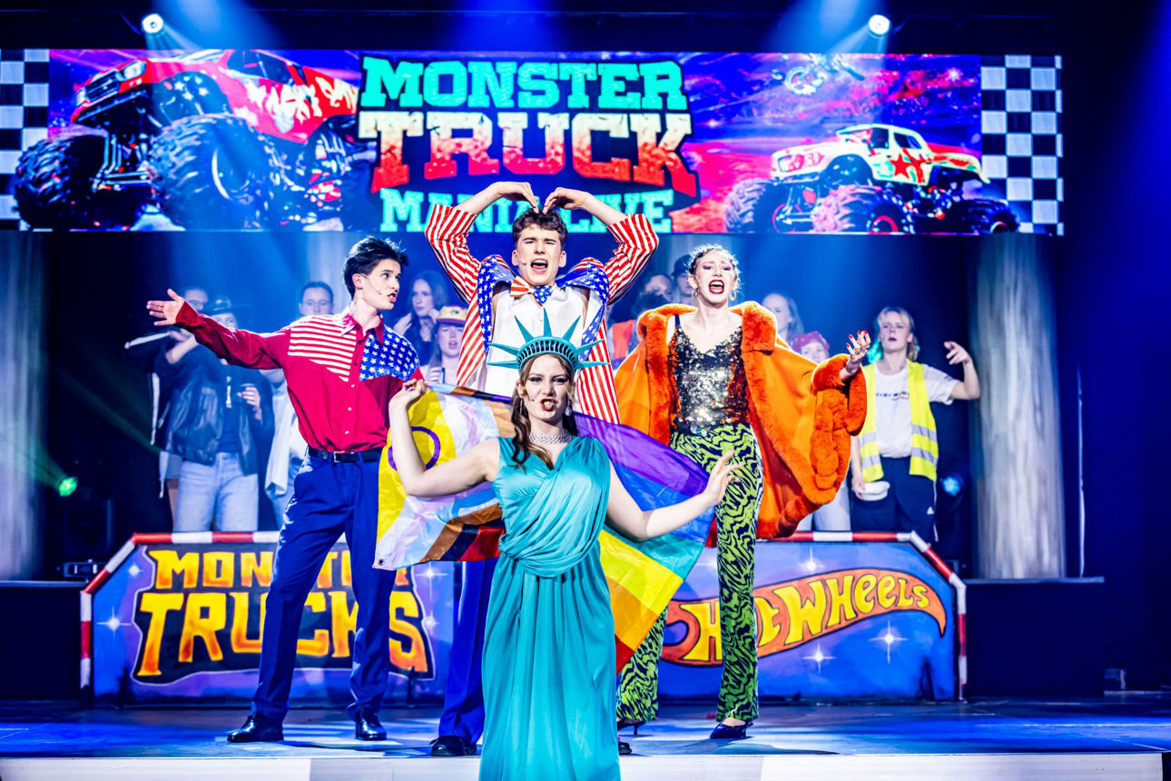 Bunter Schriftzug MonsterTruck, davor vier singende Darsteller in Kostümen, darunter die Freiheitsstatue