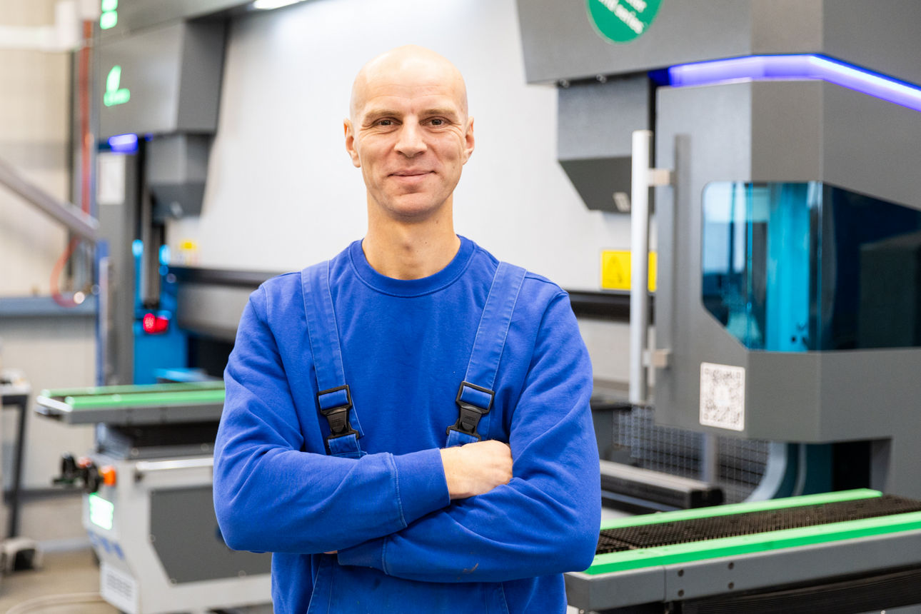 Sebastian Herrlich befindet sich im Produktionsbereich der „Herrlich GmbH“ vor einer modernen Abkantpresse. Die Aufnahme zeigt die Metallbearbeitungsanlage im laufenden Fertigungsumfeld mit Fokus auf präzise Blechbearbeitung und industrielle Produktionstechnik
