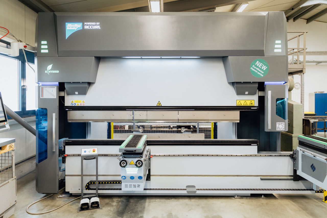 Frontansicht einer modernen CNC‑Abkantpresse im Produktionsbereich der „Herrlich GmbH“, eingesetzt für die industrielle Metall‑ und Blechbearbeitung. Sichtbar sind die Maschinenfront, Bedienelemente sowie der Arbeitsbereich der Anlage im Fertigungsumfeld