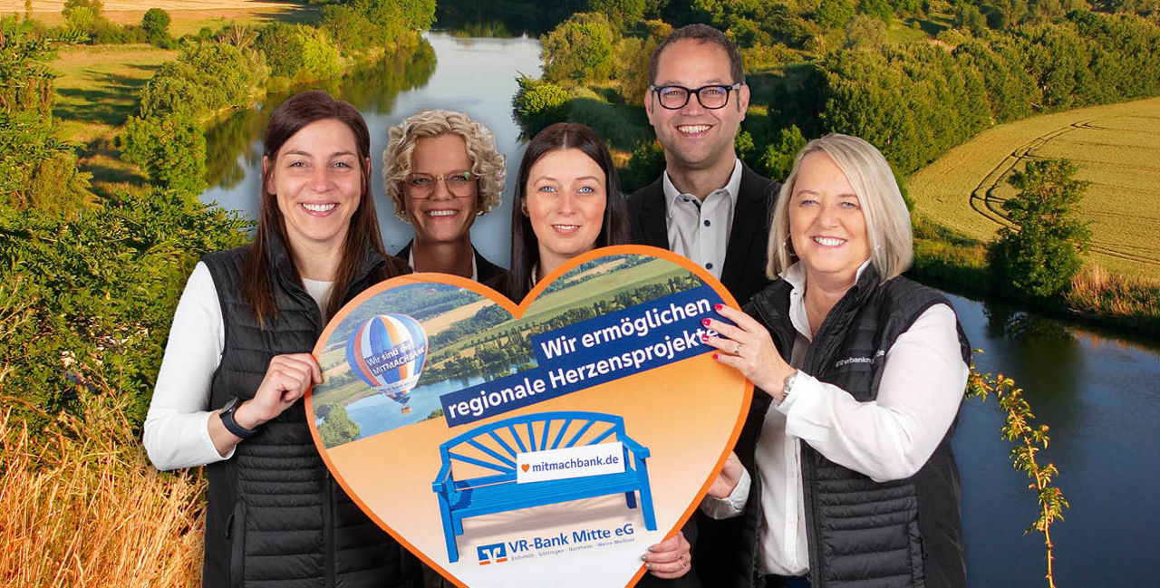 Fünf Personen halten einen herzförmigen Scheck