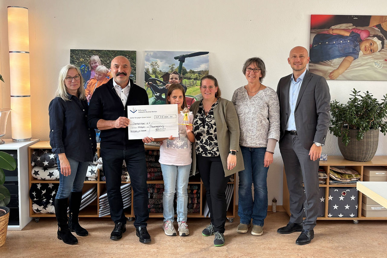 Mitglieder des Sterneninsel e.V. sowie Bodo Common und Dimitrios Meletoudis von der Stiftung der Volksbank Bruchsal-Bretten halten den überreichten Spendenscheck hoch.