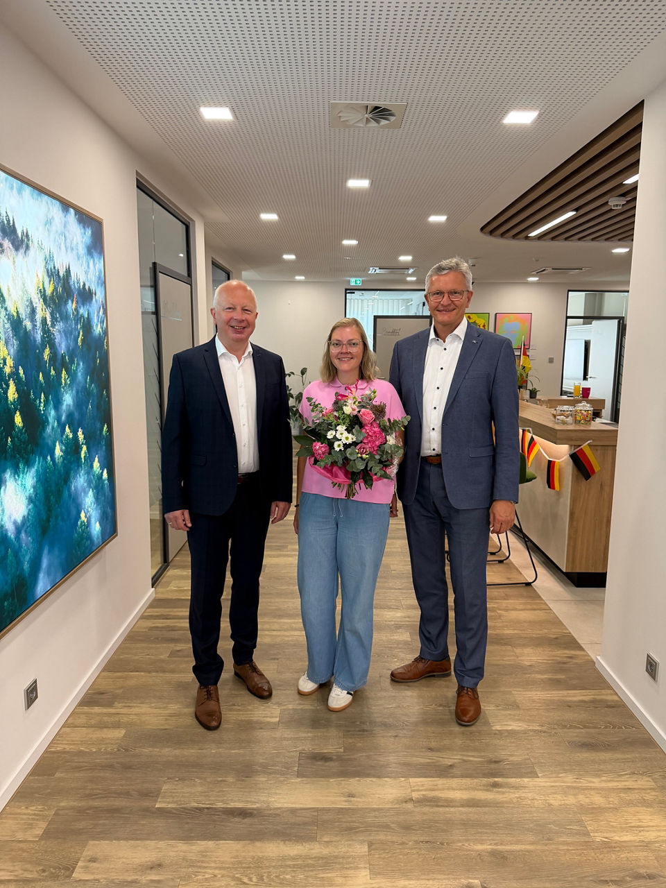 Mehrere Personen haben sich zum Foto aufgestellt. Eine Frau in der Mitte hat einen Blumenstrauß.