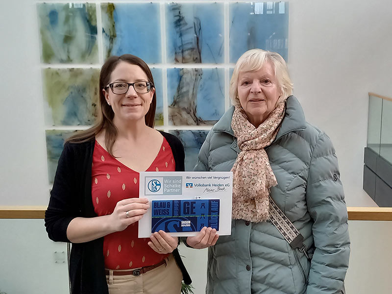 Zwei Frauen sind zu sehen, die ein Schild mit den Namen „BLAU & EGER WEISS“ halten. 