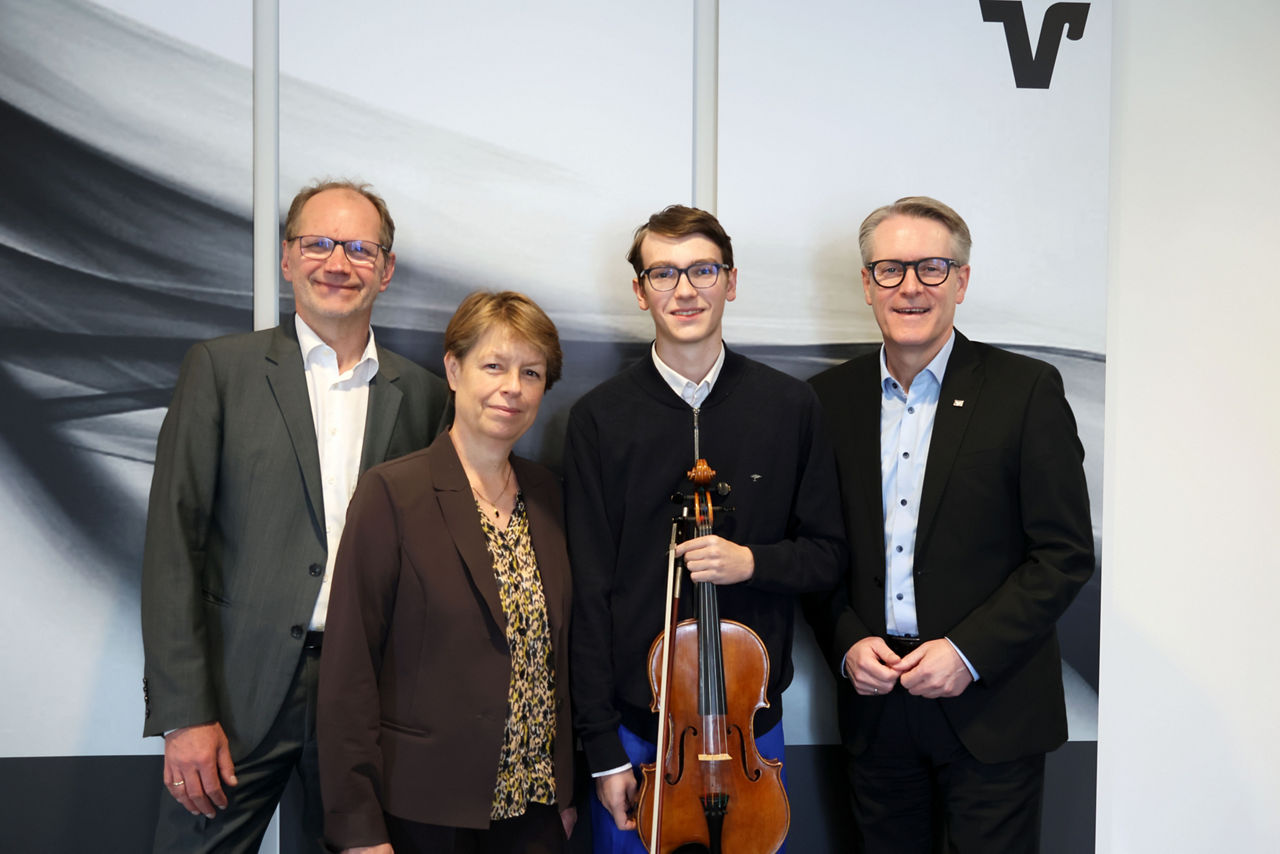 Ein junger Musiker steht mit seiner Viola zwischen Vertreterinnen und Vertretern der VerbundVolksbank OWL Stiftung und der Hochschule für Musik Detmold.