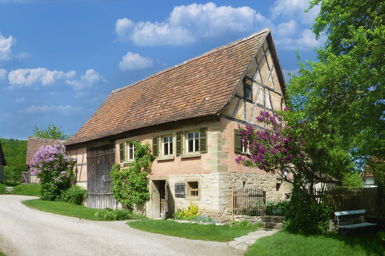 Ein altes Fachwerkhaus mit kleinem Garten wird bei Sonnenschein angestrahlt