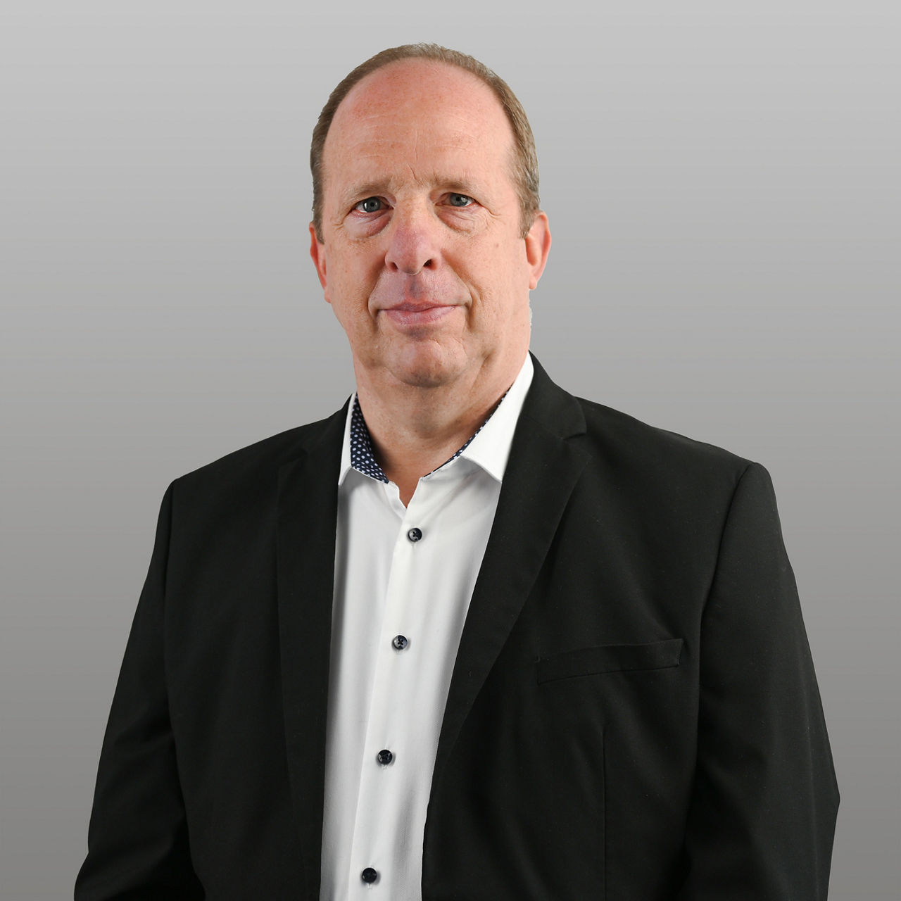 Firmenkundenberater Ludger Holz vor grauem Hintergrund