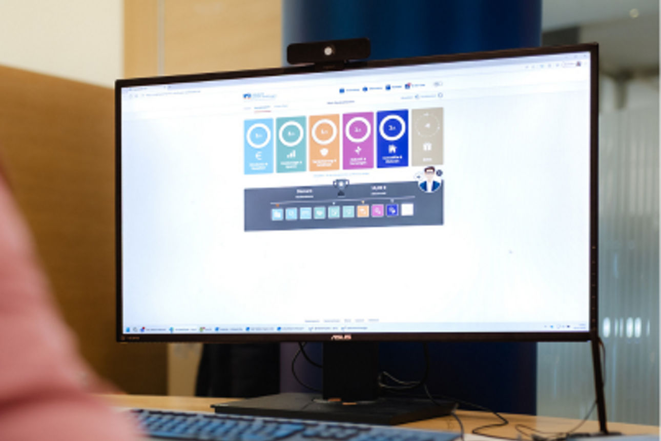 Eine Person prüft am PC-Bildschirm den Status ihres Hausbankprogramms.