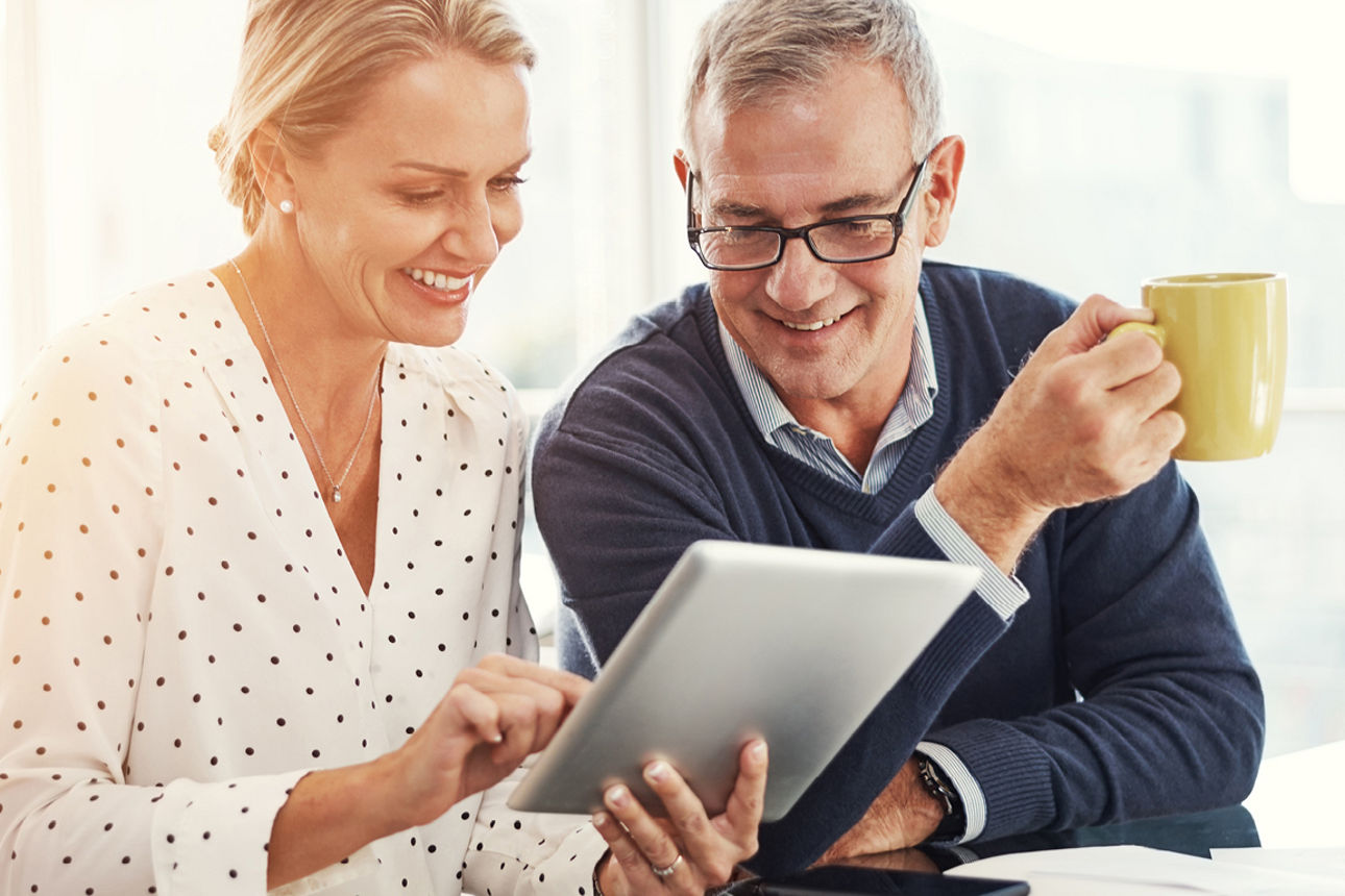 Ehepaar schaut zusammen in ein Tablet und ein 2,5 Gramm Goldbarren wird präsentiert 