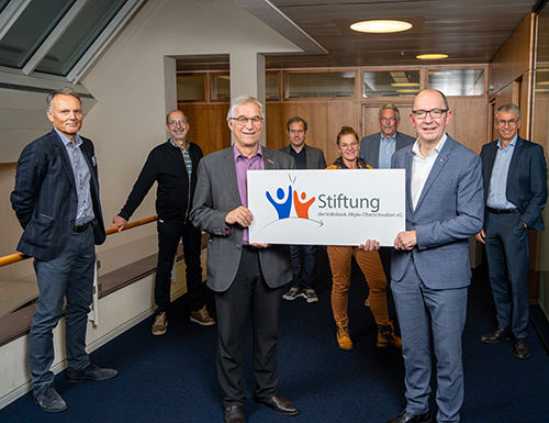 Mehrere Personen stehen in einer Reihe und halten ein Plakat mit dem Aufdruck "Stiftung" hoch.