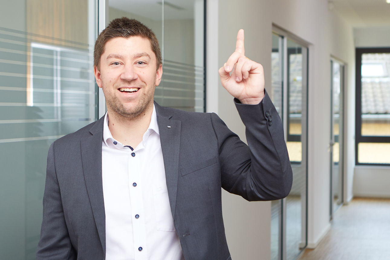 Junger Mann hebt den Finger, um zu zeigen, dass er eine gute Idee hat