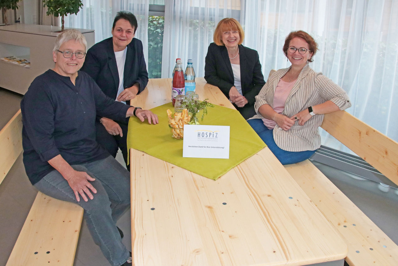 Mitarbeiter des Hospiz mit einer Bankangestellten sitzend an der neuen Sitzgruppe