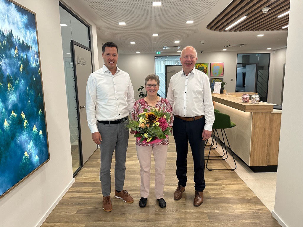 Zwei Männer und eine Frau in der Mitte mit Blumenstrauss