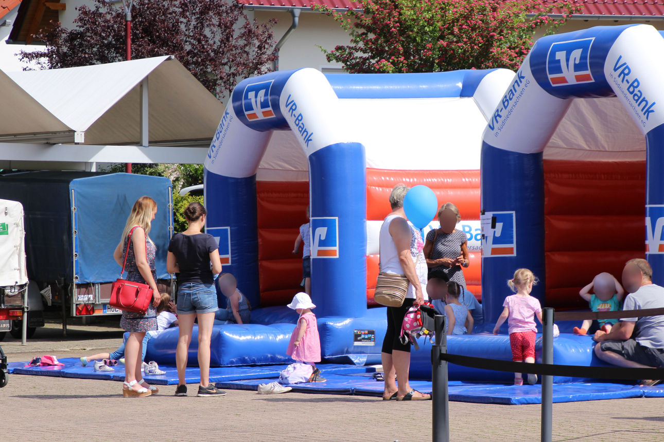 Eltern stehen vor der Hüpfburg und schauen Kindern beim spielen zu