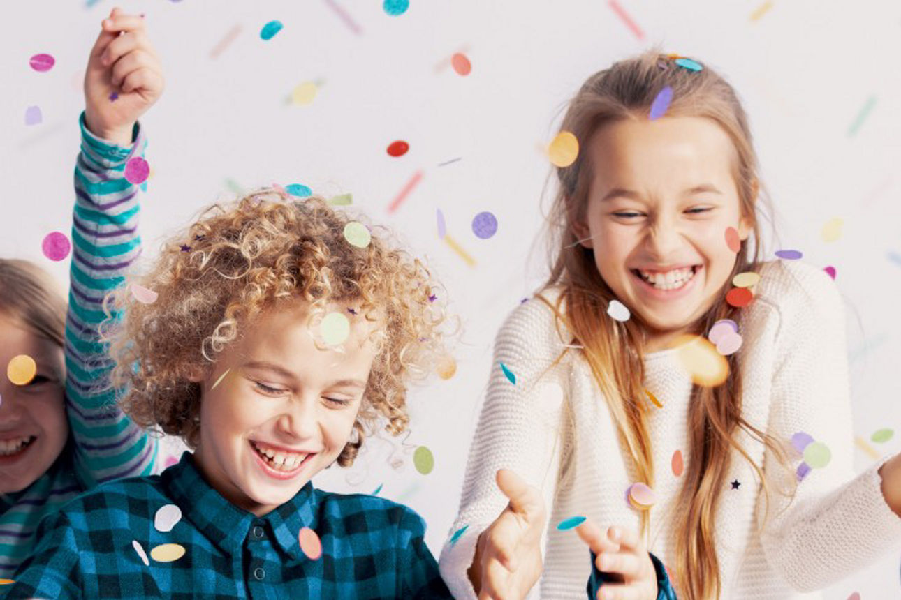 Gruppe von Kindern, die sich freuen und mit Konfetti werfen.