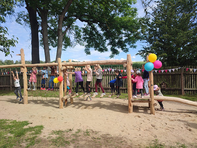 Kinder spielen an einem sonnigen Tag mit Luftballons auf hölzernen Affenstangen