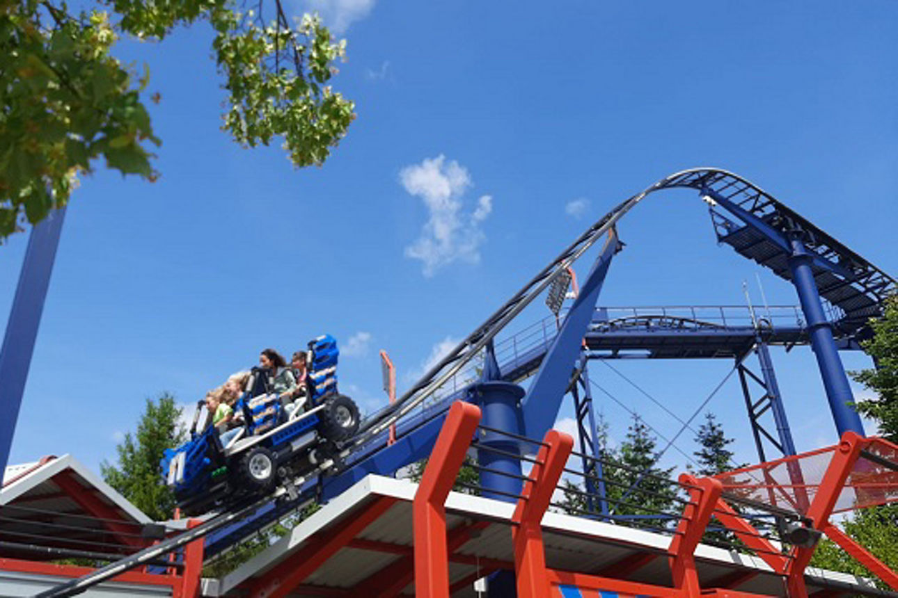 Ein blauer und roter Untersetzer erklimmt eine steile Steigung, ein sonniger Tag bietet die Kulisse.