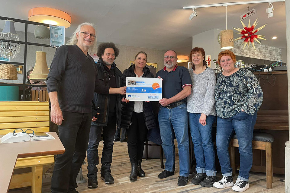 Menschen stehen aufgereiht und halten die Crowdfunding-Tafel in den Händen