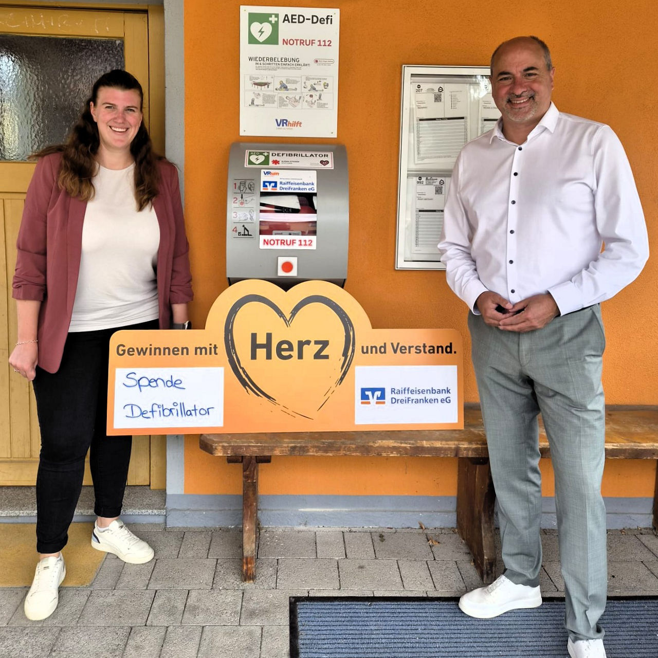 Sabine Hofmann steht mit Johannes Krapp vor einem Defibrillator