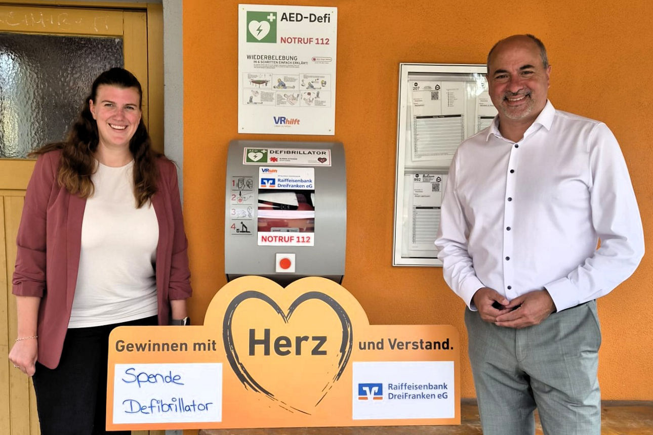 Sabine Hofmann steht mit Johannes Krapp vor einem Defibrillator
