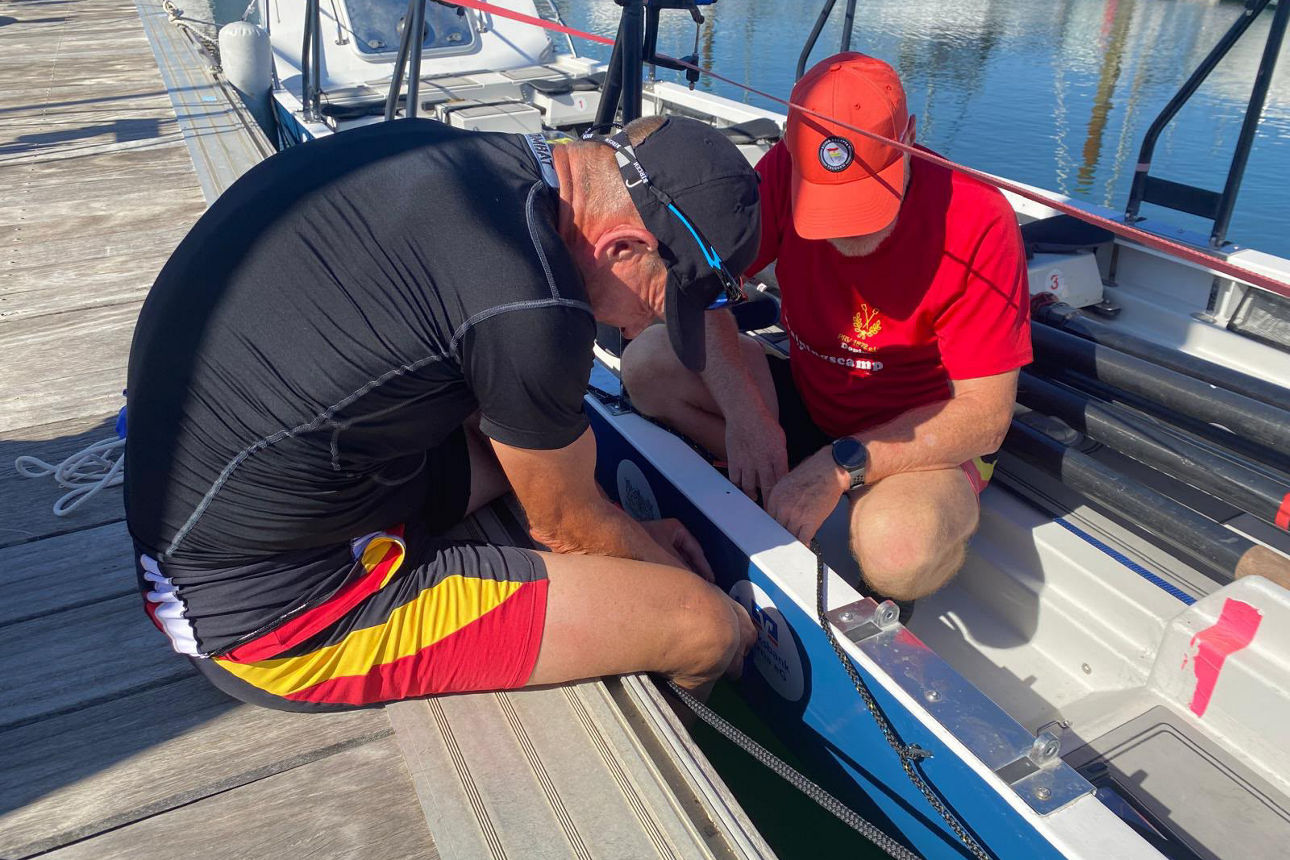 Zwei Männer schauen sich hockens das Ruderboot an.