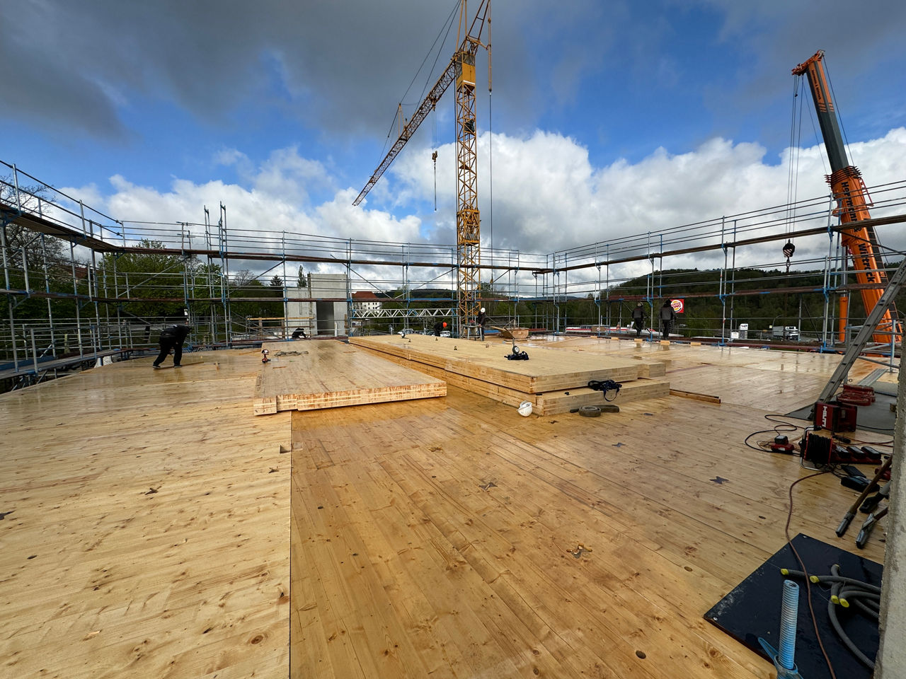 Holzplanken liegen auf dem Boden ein Kran im hintergrund