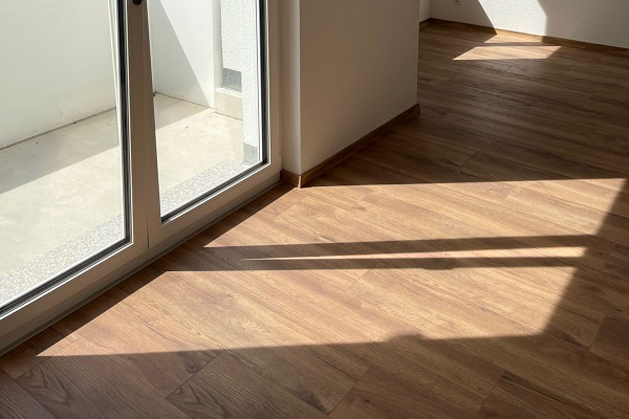 Zimmer mit Parkettboden, natürlichem Licht und Blick auf die Umgebung vom Balkon aus