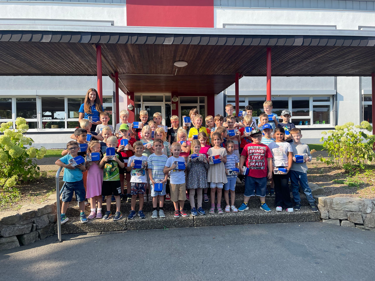Eine Gruppe von Kindern und Erwachsenen lächelt und posiert gemeinsam für ein Foto im Freien.