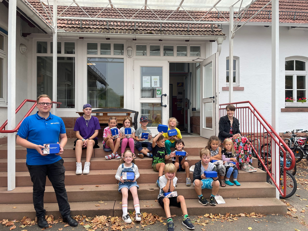 Eine bunt gemischte Gruppe von Kindern und Erwachsenen, die gemeinsam auf einer Treppe sitzen