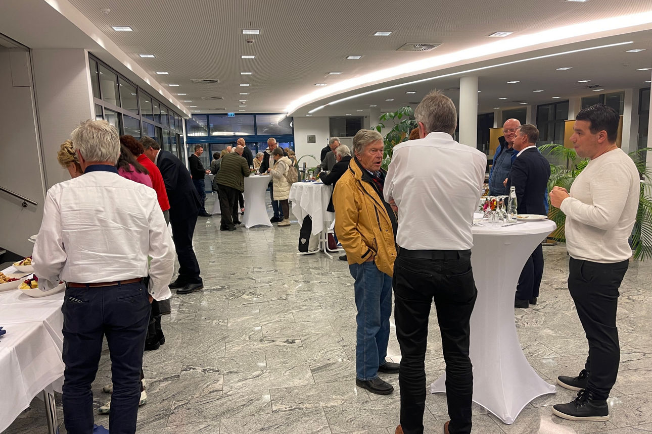 Teilnehmer tauschen sich an Stehtischen aus und bedienen sich am Buffet