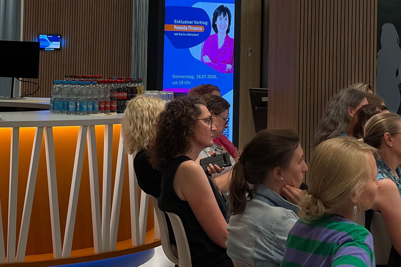 Ankündigung des Vortrags von Karina Metzdorf auf einem Display in der Filiale