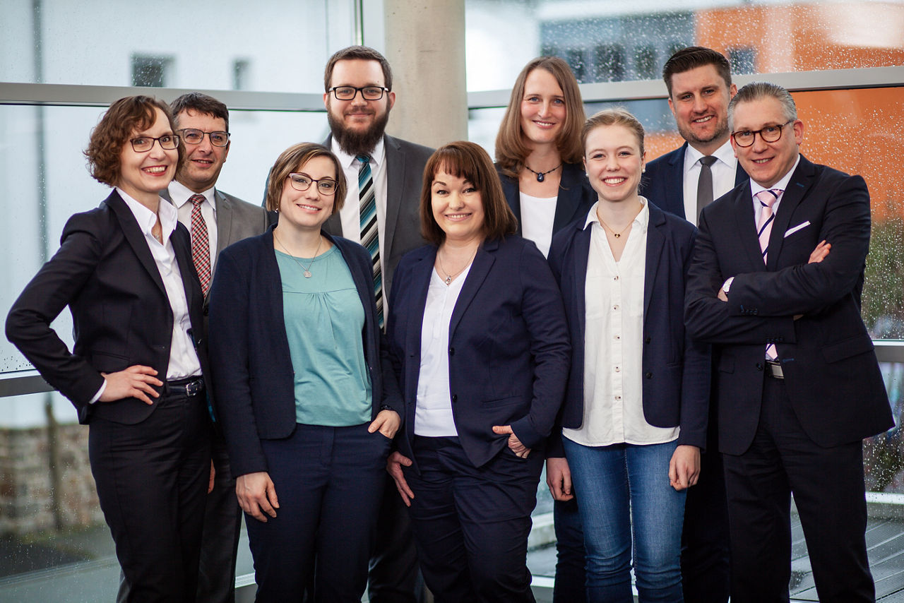 Das lächelnde Team der SKB vor einem Fenster