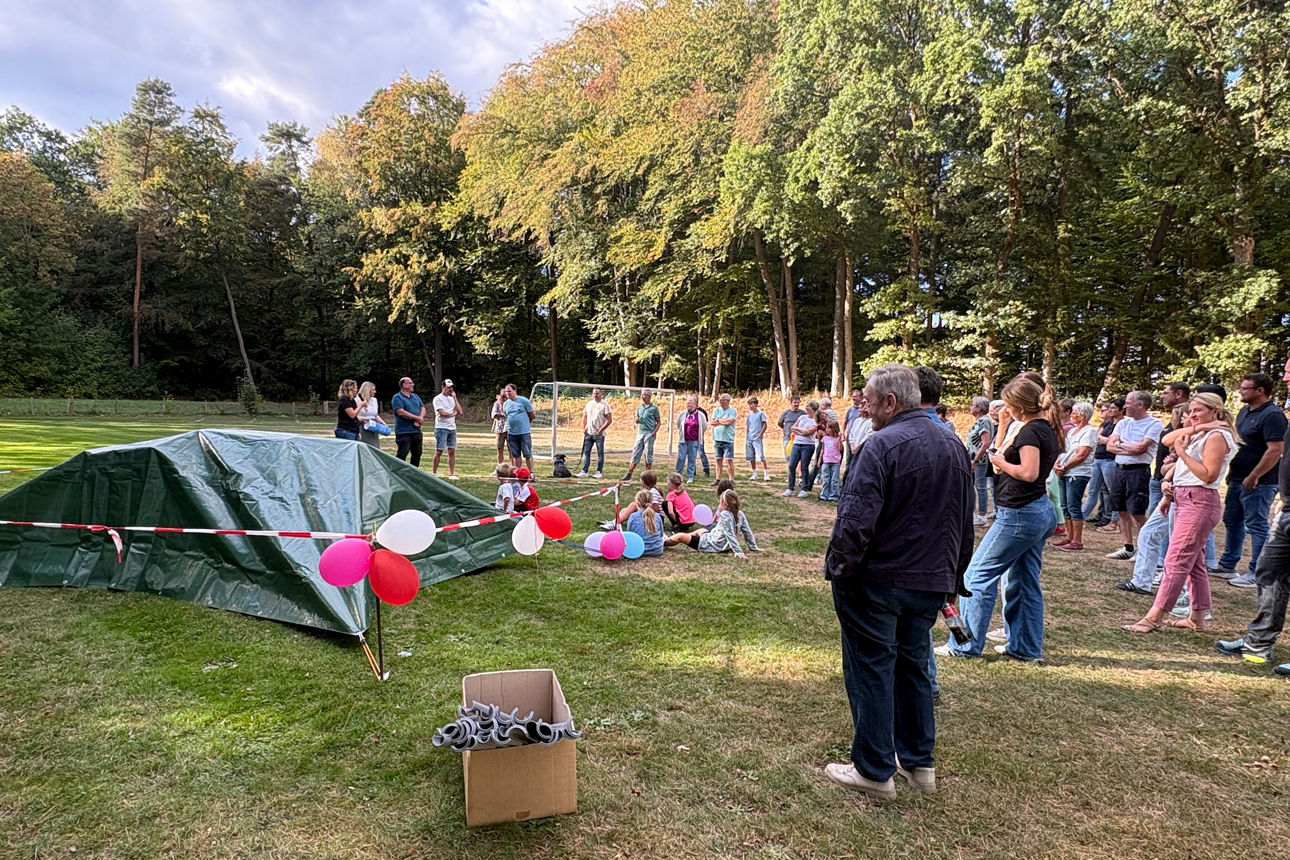 Viele Menschen und Kinder versammeln sich auf dem Sportplatz zur Spendenübergabe.