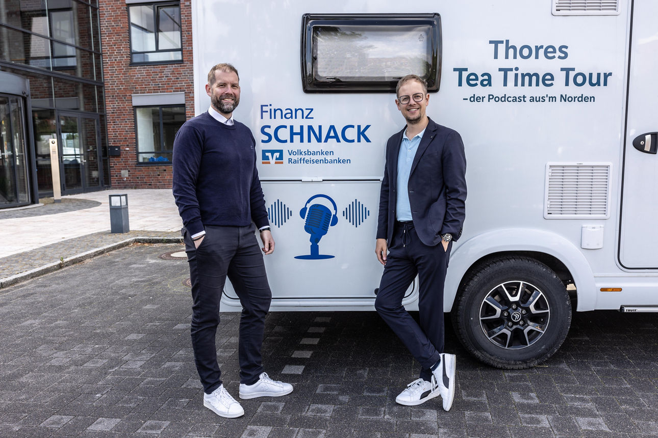 Zwei Männer stehen vor einem Wohnmobil, das mit dem Aufdruck "Finanz Schnack" versehen ist.