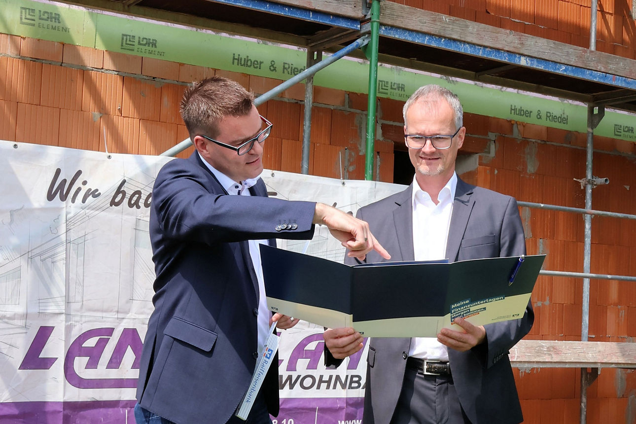 Berater Ulrich Gagstetter und Jürgen Hertlein stehen vor Rohbau