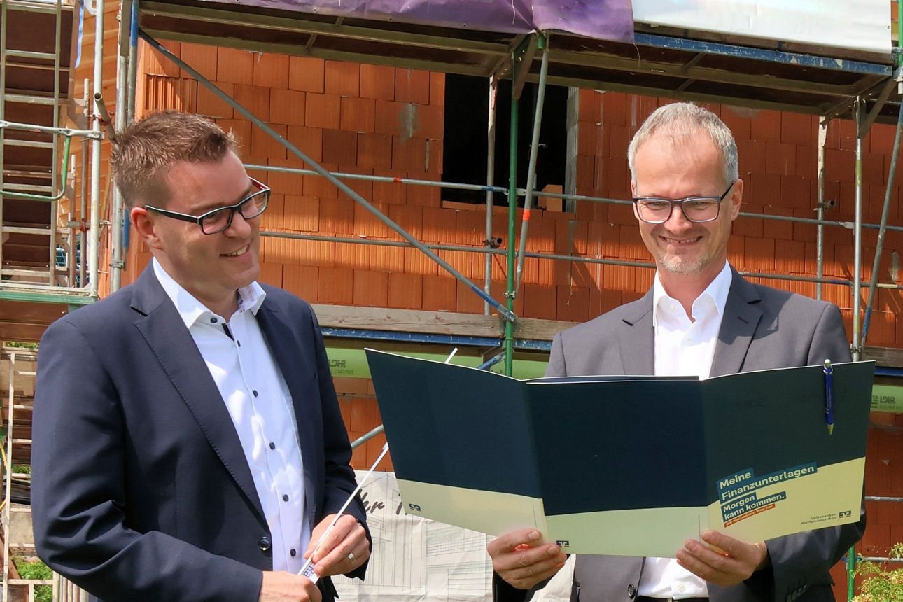 Bauherr mit Bankberater vor Neubau