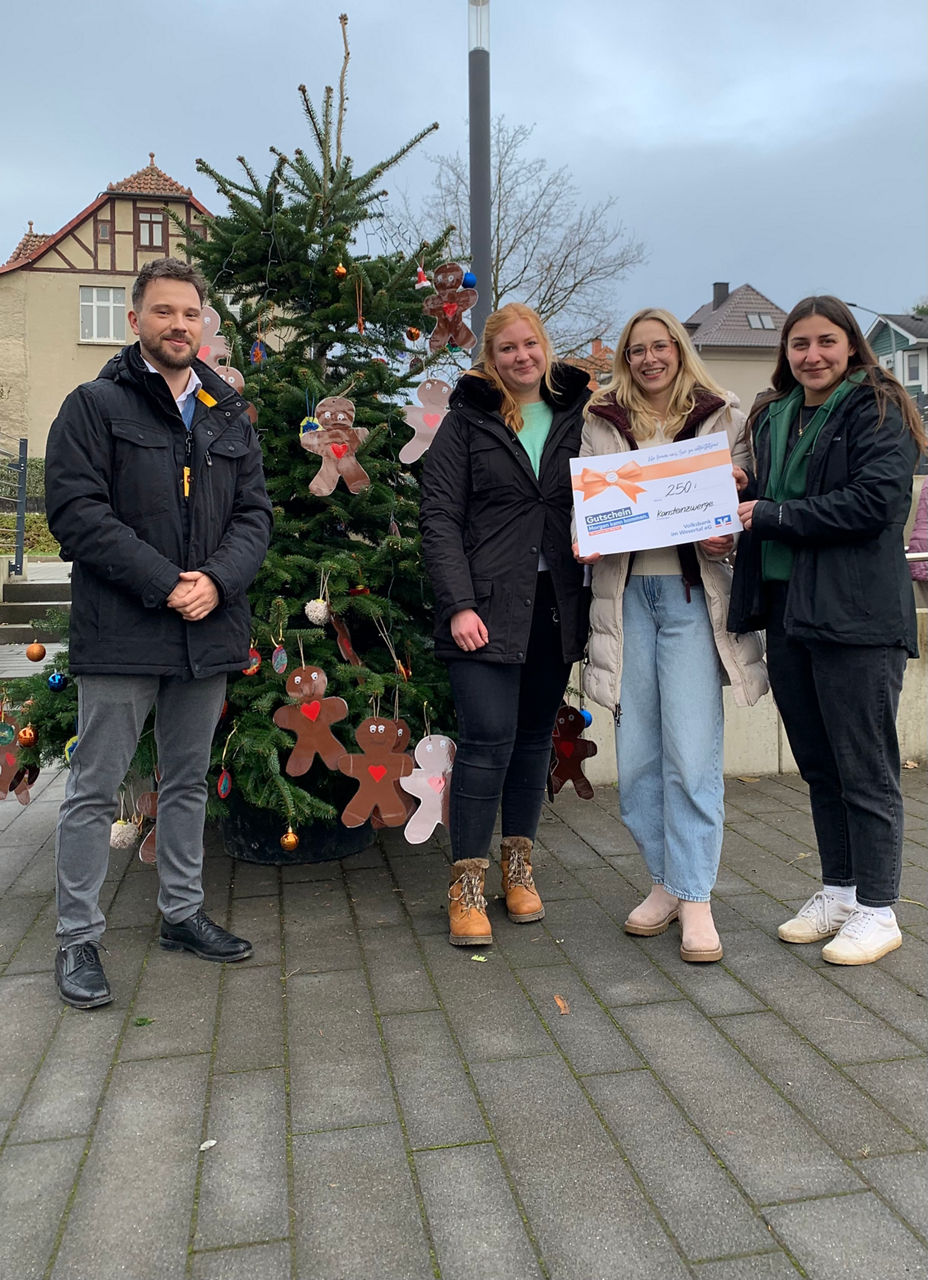 Vier Personen stehen vor einem Weihnachtsbaum