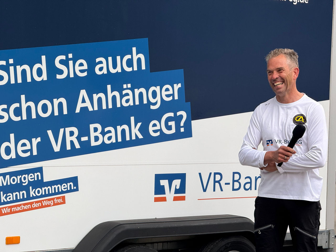 Holger Sievers neben dem 'Rad macht Schule'-Anhänger der VR-Bank eG