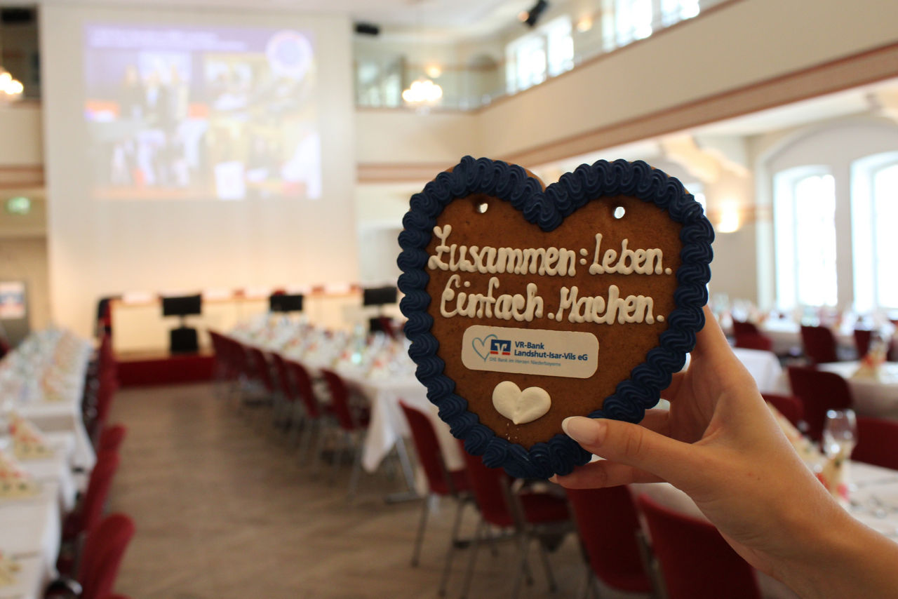 Ein Lebkuchenherz mit blauer Umrandung auf dem steht "Zusammen: Leben, Einfach, Machen."  