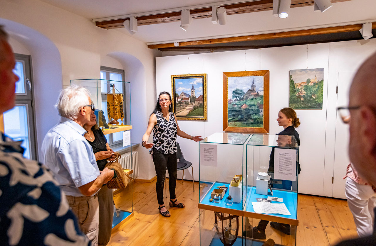 Blick in einen Museumsraum, eine Frau gibt Informationen zu den Exponaten