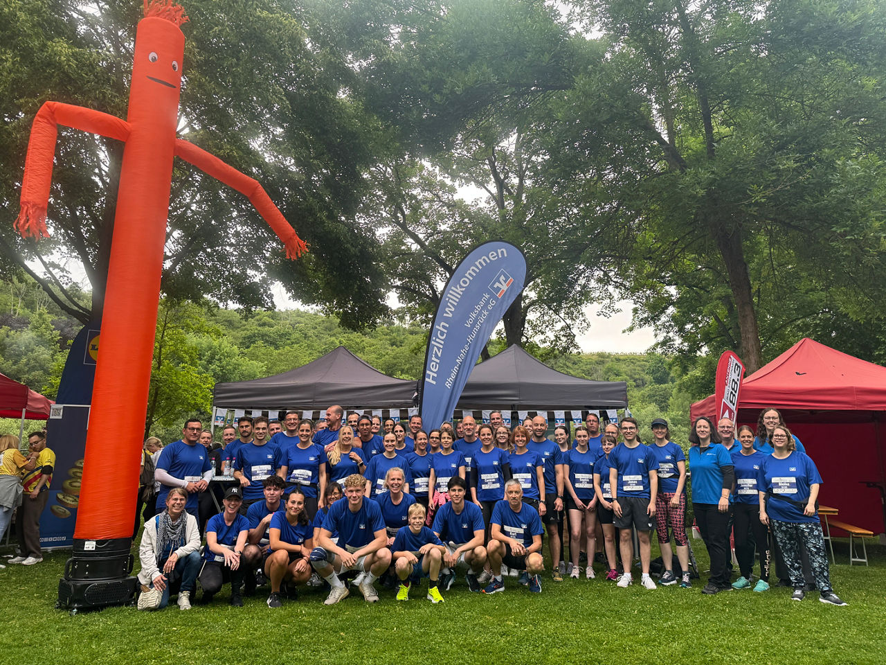Lachende Gruppe von Mitarbeitenden in blauen Trikots der Volksbank beim Firmenlauf Bad Kreuznach