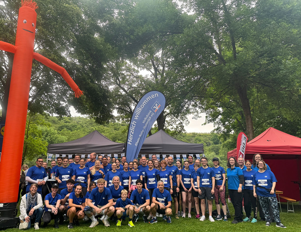 Lachende Gruppe von Mitarbeitenden in blauen Trikots der Volksbank beim Firmenlauf Bad Kreuznach