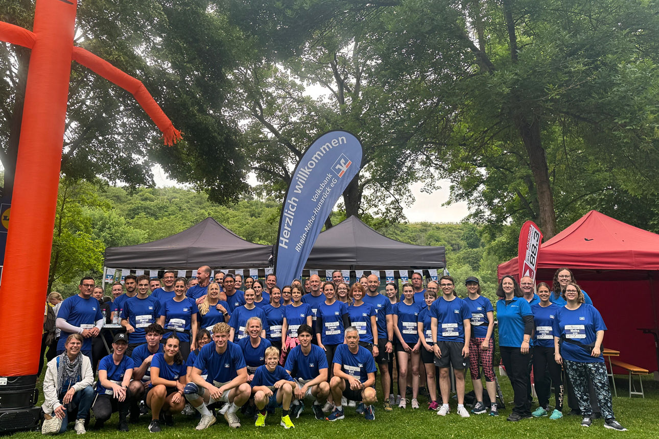 Lachende Gruppe von Mitarbeitenden in blauen Trikots der Volksbank beim Firmenlauf Bad Kreuznach