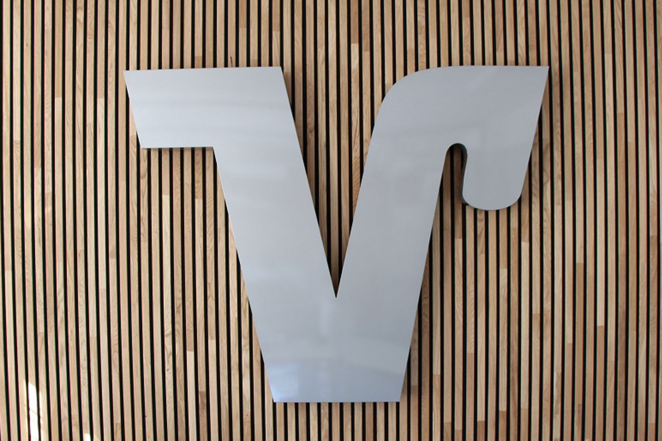 Markenzeichen Volksbanken Raiffeisenbanken auf einer Wand aus Holzpaneelen