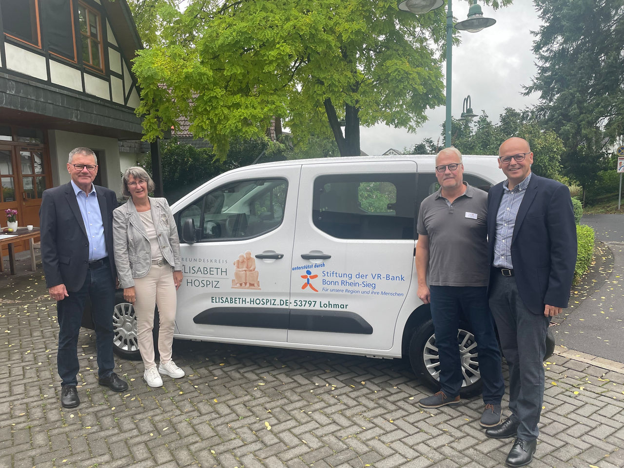Zeigt vier Personen vor einem Auto