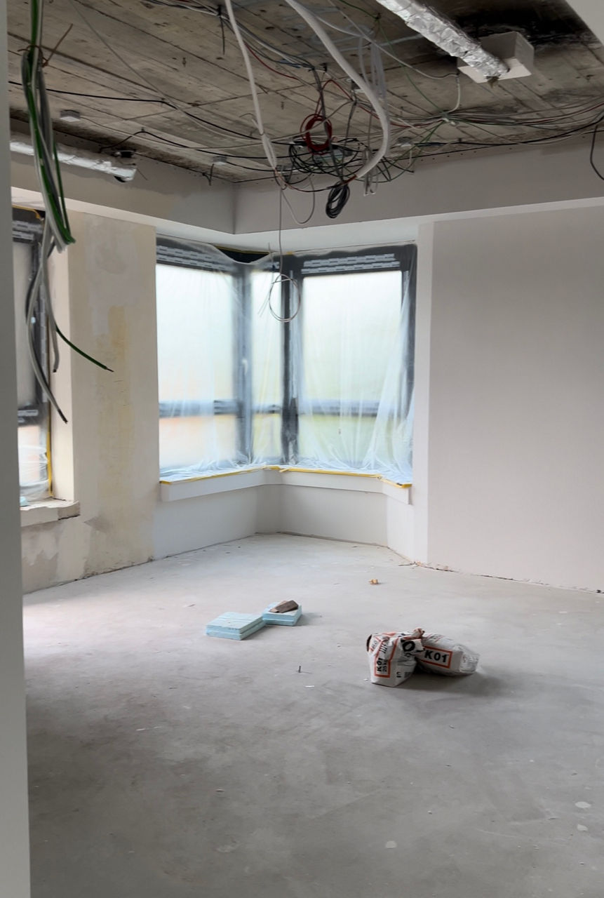 Das Foto zeigt einen leeren Raum. Neue Fenster sind eingebaut worden, während von der Decke noch Kabel hängen.